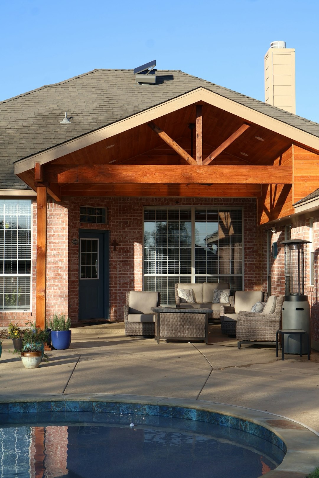House exterior with covered patio, outdoor furniture, and swimming pool.